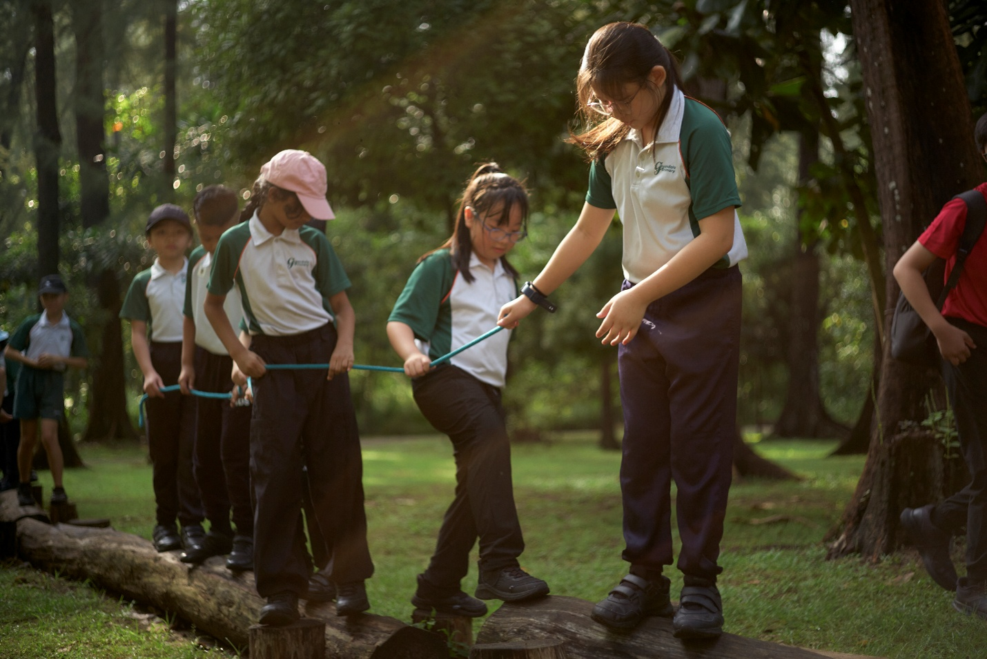 Students balancing on logs together during an outdoor team-building activity.